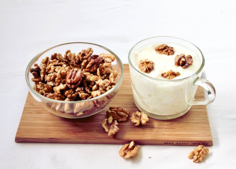 Primer plano de un montón de nueces con cáscara en una cesta de mimbre.