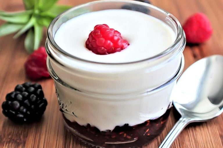 Dos tarros de cristal llenos de crema vegetal sobre madera, uno con tapa dorada y otro con tapa violeta.