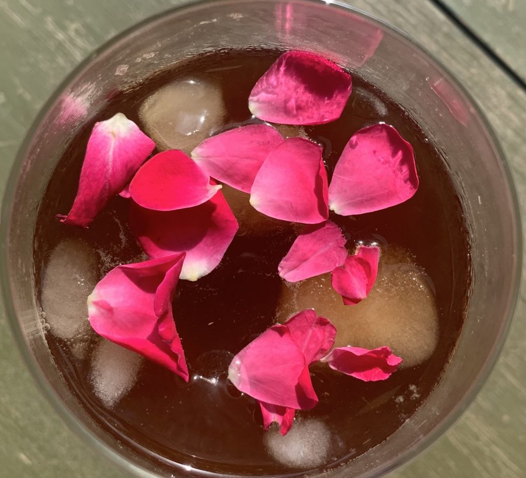 vaso con hielos y café adornado con pétalos de rosa