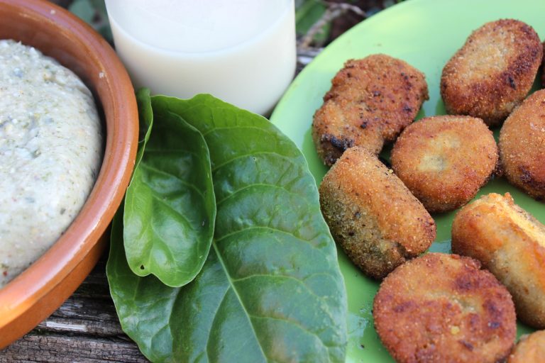 plato de croquetas junto a una botella de leche de avena y hojas de acelga