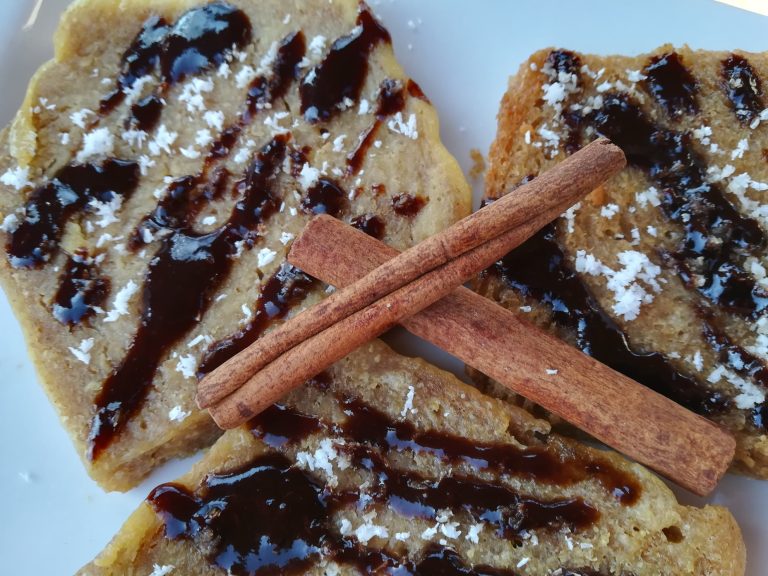 torrijas sobre plato blanco con ramas de canela y salpicón de chocolate